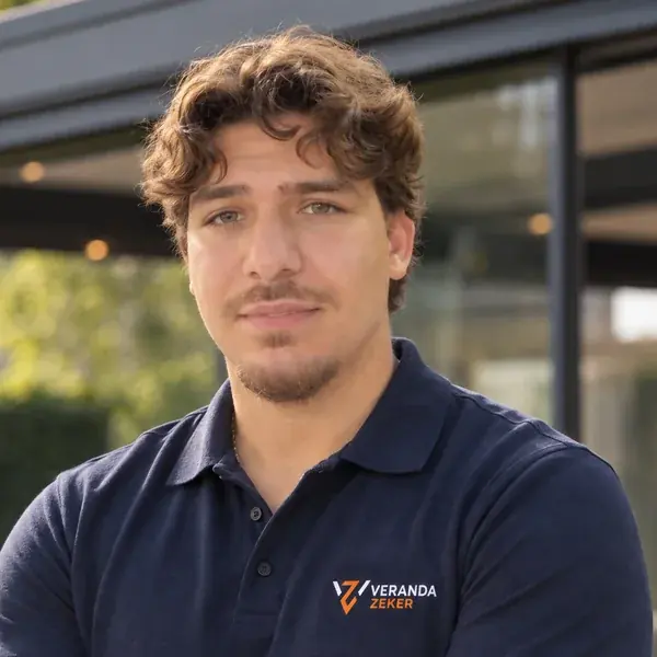Emir, Geschäftsführer von VerandaSicher, im VerandaSicher-Poloshirt vor einer Aluminium-Veranda
