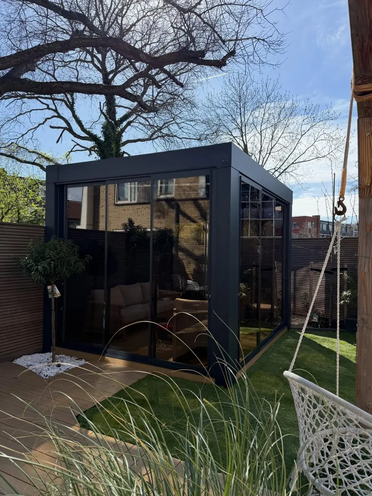 Frei stehende Cube-Veranda mit klaren Glaswänden in einem Stadtgarten