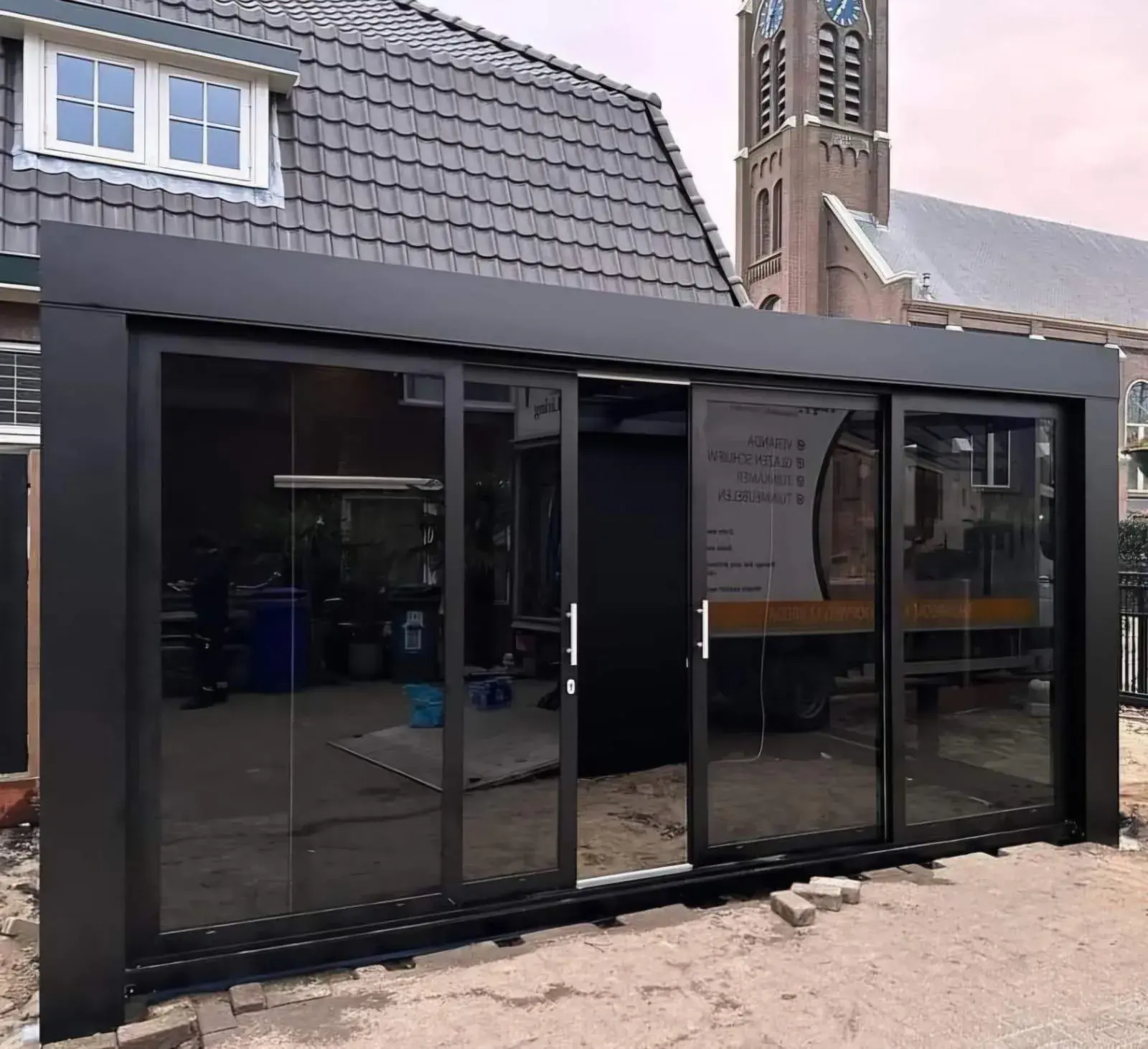 Schwarze Aluminium-Überdachung mit Glasschiebetüren an einem Haus