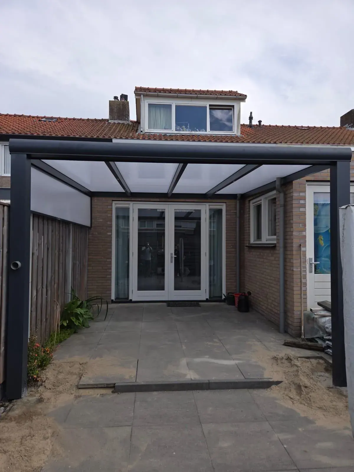 Veranda mit Glasdach und Sonnenschutz in sommerlicher Sonne