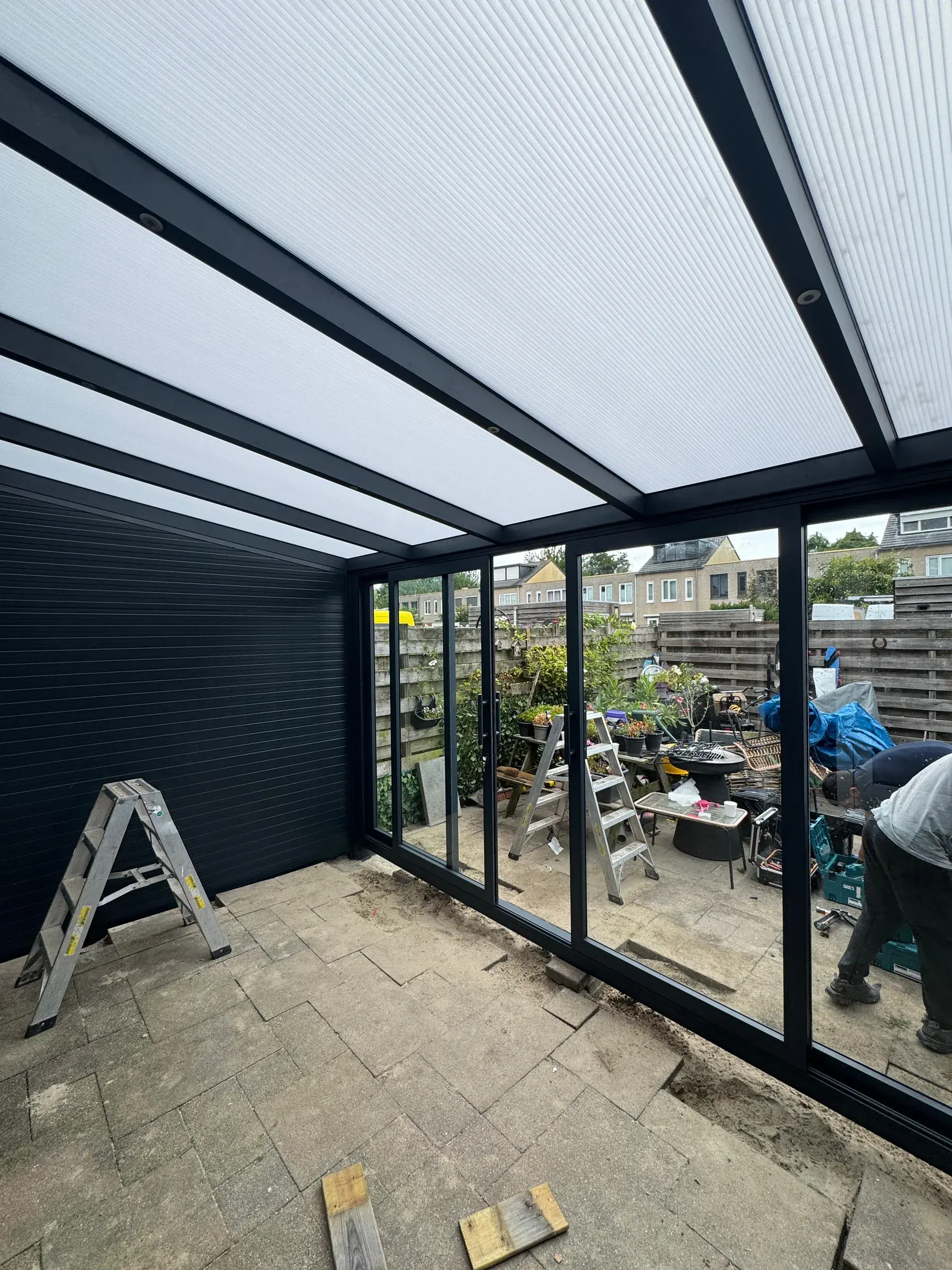 Veranda mit Polycarbonat-Dach und Glaswänden während der Montage